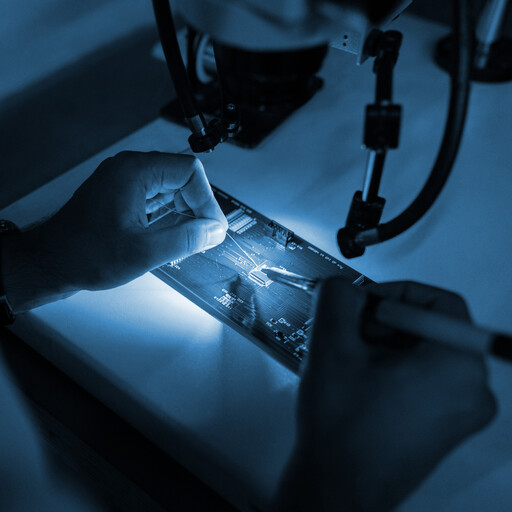 Close-up of worker soldering chip to circuit board